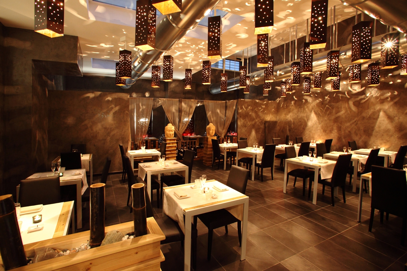 Sala del ristorante Megumi con canali in acciaio a vista e lampade sospese